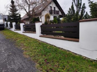 Nowoczesne ogrodzenie czarne aluminiowe OK 063 na białym murowanym cokole przed domem