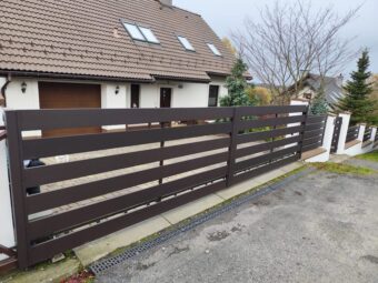 Nowoczesne ogrodzenie czarne aluminiowe z bramą przesuwną przed domem jednorodzinnym